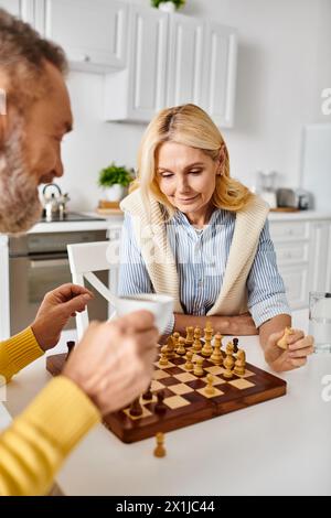 A mature loving couple in cozy homewear engrossed in a game of chess, strategizing and contemplating their moves. Stock Photo