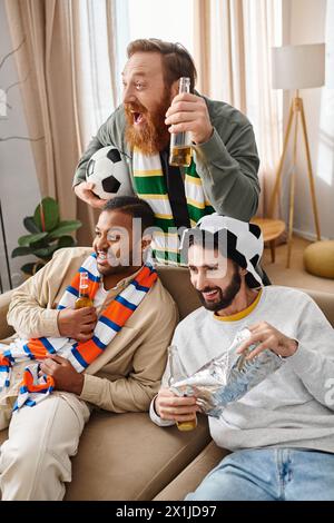 Three handsome, cheerful men of different ethnicities sit atop a couch, radiating warmth and friendship in a casual setting. Stock Photo