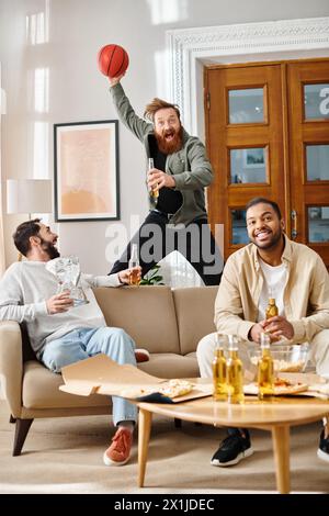 Three handsome men of different ethnicities chatting and laughing together in a cozy living room, showcasing friendship and camaraderie. Stock Photo