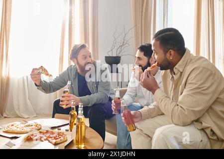 Three cheerful, handsome men of different ethnicities laughing and eating pizza together at a table in casual attire. Stock Photo
