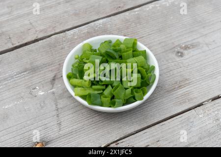 White bowl with sliced ​​spring onions on a light wooden background Stock Photo