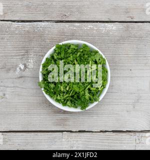 sliced ​​fresh curly parsley on a light wooden background Stock Photo