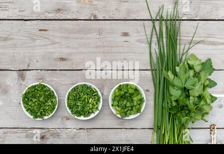 Bunch and sliced ​​fresh fresh parsley, chives and spring onion on a light wooden background Stock Photo