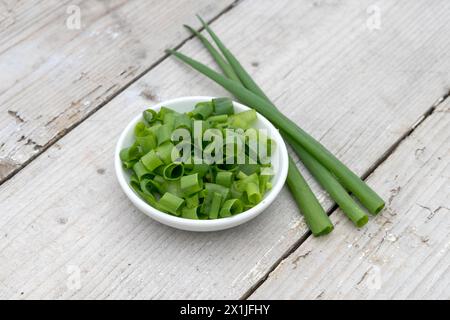 White bowl with sliced ​​spring onions on a light wooden background Stock Photo
