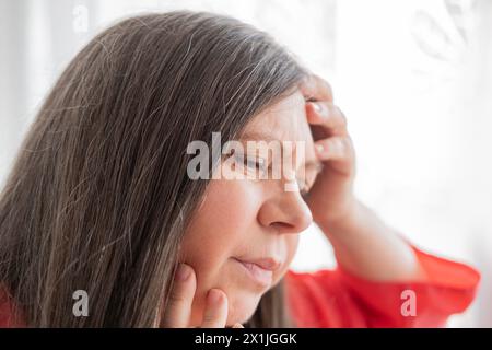 diseased mature woman experiences severe headache, holding head, Hot flashes during menopause, Decreased memory and concentration, feeling nervous, Fe Stock Photo