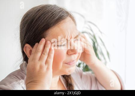 diseased mature woman experiences severe headache, holding head, Hot flashes during menopause, Decreased memory and concentration, feeling nervous, Fe Stock Photo