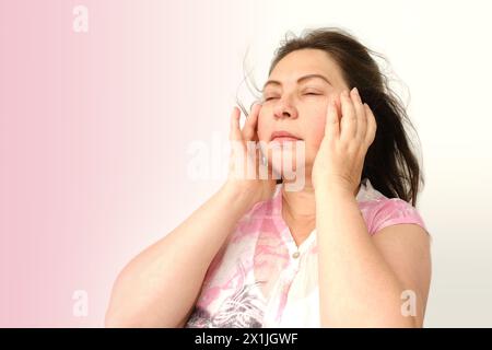 diseased mature woman experiences severe headache, holding head, Hot flashes during menopause, Decreased memory and concentration, feeling nervous, Fe Stock Photo