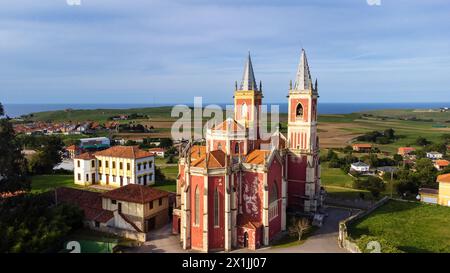 An aerial view of the bright red Parish Church of San Pedro Ad Venceya with two towers. Cóbreces, Cantabria, Spain. Stock Photo