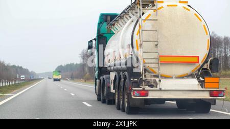 A truck with a semi-trailer tanker transports dangerous cargo along the highway - liquefied gas. Logistics of dangerous goods Stock Photo