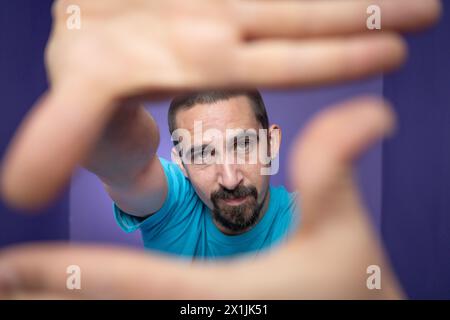 Young man doing frame using hands and fingers, isolated over purple background Stock Photo