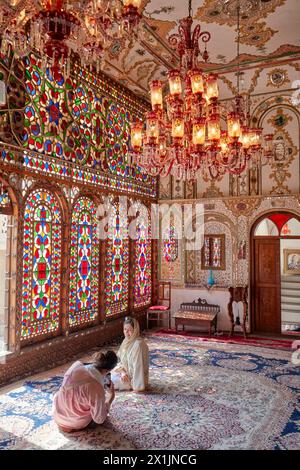Tourists do a portrait photo session in ornate reception hall (shahneshin) with stained glass windows in Mollabashi Historical House. Isfahan, Iran. Stock Photo