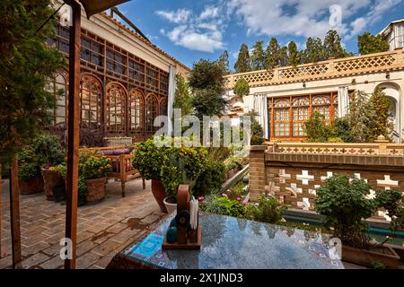 Upper outdoor terrace with many green houseplants in a traditional Iranian house now turned into an upscale boutique hotel. Isfahan, Iran. Stock Photo