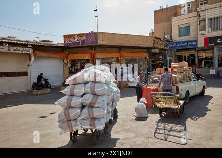 A porter pulls his heavily loaded cart in a street near the Grand Bazaar of Isfahan, Iran. Stock Photo