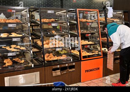 Customer selecting pastries and snacks from self service bins which prevent handling in supermarket Stock Photo