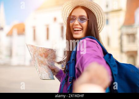 Excited woman using map and extending hand Stock Photo