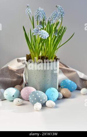 Easter eggs and light blue muscari flowers in cup on a white table. Easter still life Stock Photo