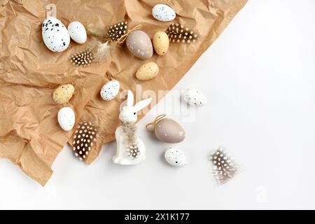 Easter composition with white rabbit, eggs and feathers on a brown kraft paper background on a white table. Top view. For easter greeting cards with c Stock Photo