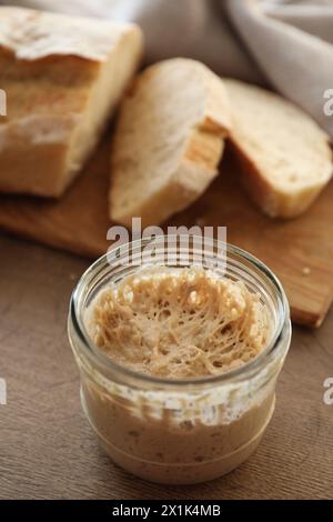 Sourdough starter in glass jar on wooden table Stock Photo