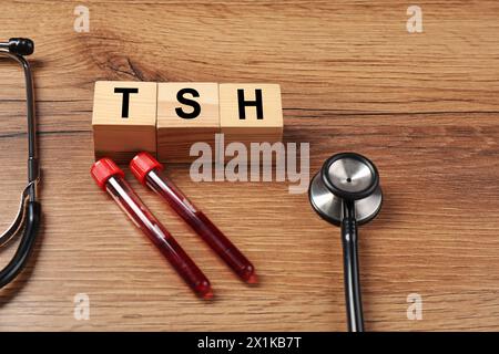 Endocrinology. Stethoscope, cubes with thyroid hormones and blood samples in test tubes on wooden table Stock Photo