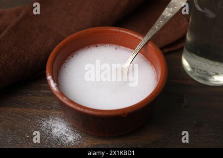 Chemical reaction of vinegar and baking soda in bowl on wooden table, closeup Stock Photo