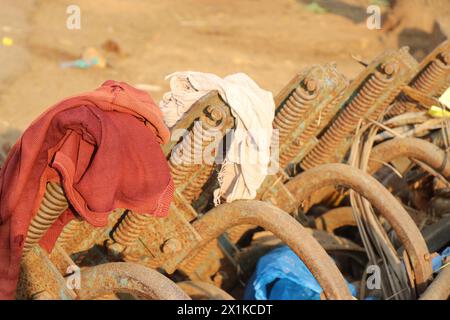 Cultivator used in tractors to dig and turn the soil upside down in an abandoned condition with waste clothes over it Stock Photo