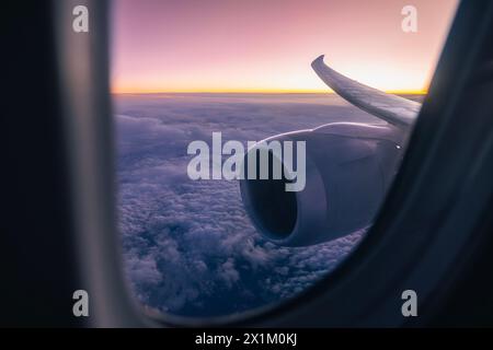 Beautiful view from airplane window over jet engine and wing. Plane flying high above clouds during dusk.Themes aviation, travel and connection. Stock Photo