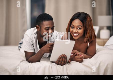 Black couple, tablet and bed in home for relax entertainment or streaming movie for resting, bonding or subscription. Man, woman and online with Stock Photo