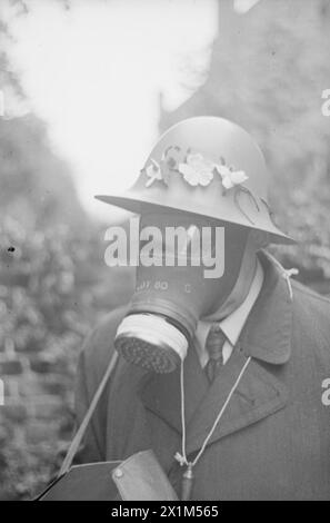 VE Day Scenes - A portrait of Arthur Lassally, in the garden of the family home, in Richmond Surrey. Arthur is wearing his Supplementary Fire Party helmet, adorned with leaves, his respirator, and his respirator haversack. A whistle, held on a length of string is worn around Arthur's neck. From up a tree to behind the camera.The image shows a dense crowd of people, gathered outside the gates of Buckingham Palace, on the 8th May, 1945 - VE-Day. The photograph was taken by Walter Lassally, a young man who had arrived in Britain, as a refugee six years earlier. Years later, Walter explained that Stock Photo