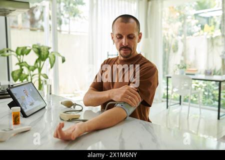 Man suffering from hypertension measuring blood pressure at home Stock Photo