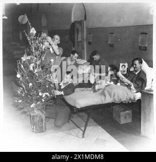 CHRISTMAS DECORATIONS - A group of patients at the 104 British General Hospital making decorations. Left to right:- Bdr.E.Stevenson of 15 Comley Road, Dartford, Kent Spr. A. Manning of 132 Hathersage Road, Beeches Estate, Birmingham (kneeling) L/Cpl. Peter Ollis of 22 High Stree, Keynsham, Nr.Bristol Pte.Taffy Madge of Troed-y-bryn, Cornoation Road, Brynaman, Ammanford, Carm. Wales. Sgt.Jay Cameron, S.African Forces of 4 Millsayd Court, 18 Terrace Road, Johannesburg, S.Africa (in bed), British Army Stock Photo