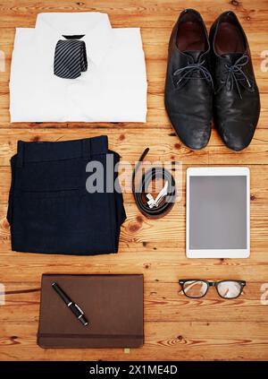 Business, items and layout on floor with clothes, tablet and notebook for work trip on wood background. Glasses, shoes and setup for corporate fashion Stock Photo