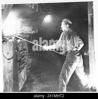 ON BOARD AN AFRICAN BOUND SHIP IN CONVOY - Fireman 'Babe' Morton raking the fires, British Army Stock Photo