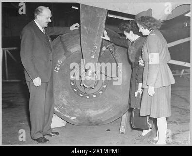 F.F.I. GIRLS VISIT HANDLEY PAGE WORKS - Picture taken at the Handley Page works in Great Britain during the visit of two F.F.I. girls - Mlle. Marguerite and Mlle.Henrietta shows - Sir Frederick Handley Page, explaining the workings of the giant undercarriage of his latest Halifax bomber to Mlle. Henriette [centre] and Mlle.Marguerite during their visit to the Handly Page works. Picture issued 1944, Royal Air Force Stock Photo