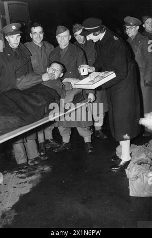 THE POLISH ARMY IN THE WESTERN DESERT CAMPAIGN, 1940-1942 - A wounded Polish soldier, probably of the Independent Carpathian Rifles Brigade, being served refreshments at a Red Cross mobile canteen by a female ambulance driver on his arrival at a London railway station, 25 January 1943. He is being carried on stretchers, on his way to a hospital from the North African Front, Polish Army, Polish Armed Forces in the West, Independent Carpathian Rifles Brigade, British Red Cross and Order of St. John of Jerusalem War Organisation Stock Photo