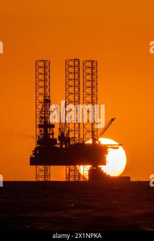 Southport, Merseyside, 04/17/2024  A beautiful sunset nestles into the horizon behind the impressive 'Rowan Norway' jack-up oil rig marine vessel located in the Liverpool Bay off the Irish Sea. This “jack-up” rig has legs 173 metres long that can be deployed to 150 metres and can drill to a depth of 10,670 metres.  The wells will be converted so that they can be reused to store carbon dioxide in the depleted oil and gas reservoirs beneath the seabed as part of a wider HyNet Carbon Capture and Storage project.  Credit: Cernan Elias/Alamy Live News Stock Photo