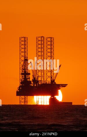 Southport, Merseyside, 04/17/2024  A beautiful sunset nestles into the horizon behind the impressive 'Rowan Norway' jack-up oil rig marine vessel located in the Liverpool Bay off the Irish Sea. This “jack-up” rig has legs 173 metres long that can be deployed to 150 metres and can drill to a depth of 10,670 metres.  The wells will be converted so that they can be reused to store carbon dioxide in the depleted oil and gas reservoirs beneath the seabed as part of a wider HyNet Carbon Capture and Storage project.  Credit: Cernan Elias/Alamy Live News Stock Photo