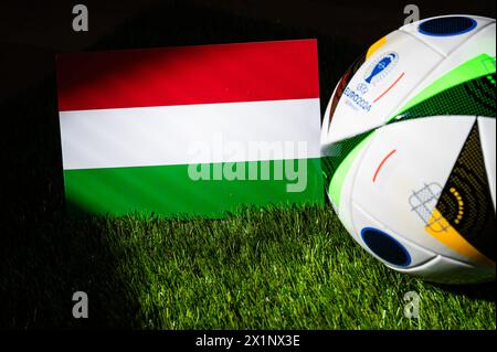 BERLIN, GERMANY, APRIL 17, 2024: Hungary national flag and official soccer ball of Euro 2024 football tournament in Germany placed on green grass. Bla Stock Photo