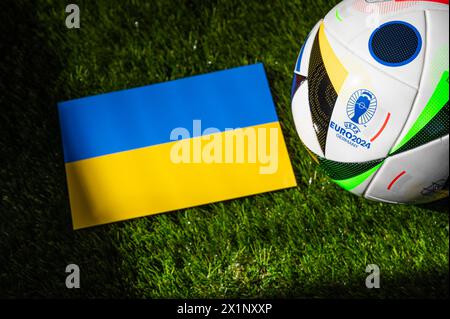 LEIPZIG, GERMANY, APRIL 17, 2024: Ukraine national flag and official soccer ball of Euro 2024 football tournament in Germany placed on green grass. Bl Stock Photo