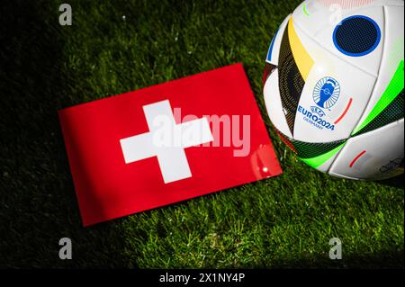 LEIPZIG, GERMANY, APRIL 17, 2024: Switzerland national flag and official soccer ball of Euro 2024 football tournament in Germany placed on green grass Stock Photo