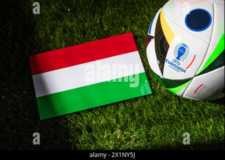LEIPZIG, GERMANY, APRIL 17, 2024: Hungary national flag and official soccer ball of Euro 2024 football tournament in Germany placed on green grass. Bl Stock Photo