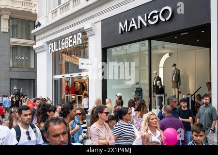 Shoppers and pedestrians walk past the spanish multinational clothing design retail company by Inditex, Pull & Bear (Pull&Bear), and Mango stores in Spain. Stock Photo