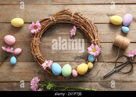 Supplies for creating Easter wreath with painted eggs and flowers on brown wooden background Stock Photo