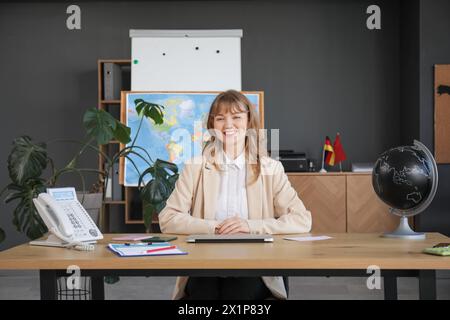 Female travel agent sitting at table in office Stock Photo
