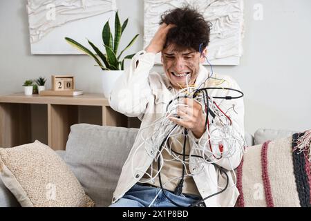 Electrocuted young man with burn face and wires at home Stock Photo