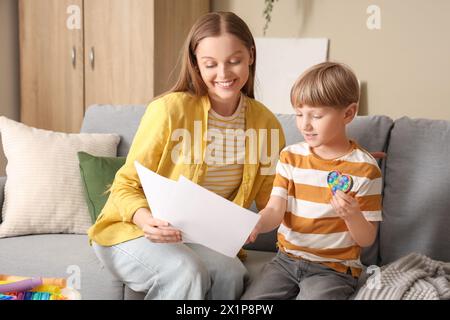 Female psychologist working with little boy on sofa in office. World Autism Awareness Day Stock Photo