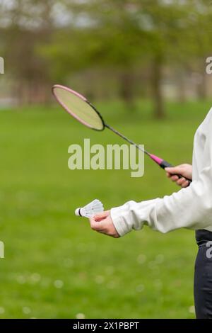 Hand with badminton racket and shuttlecock on green lawn background Stock Photo