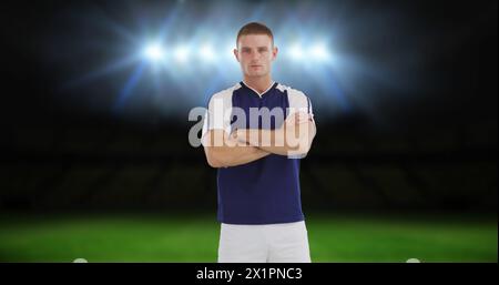 Man wearing sportswear standing with arms crossed on field Stock Photo