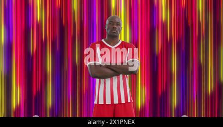 Man in red and white sports uniform standing with arms crossed, looking serious Stock Photo