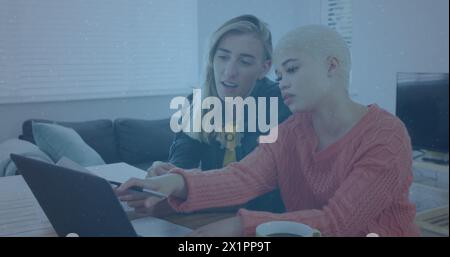 Caucasian/Biracial female friends are looking at laptop Stock Photo