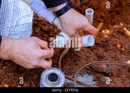 During repairs, technician plumber uses clear primer on PVC pipes before gluing them Stock Photo
